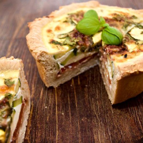 A delicious deep layered Mediterranean quiche with basil garnish